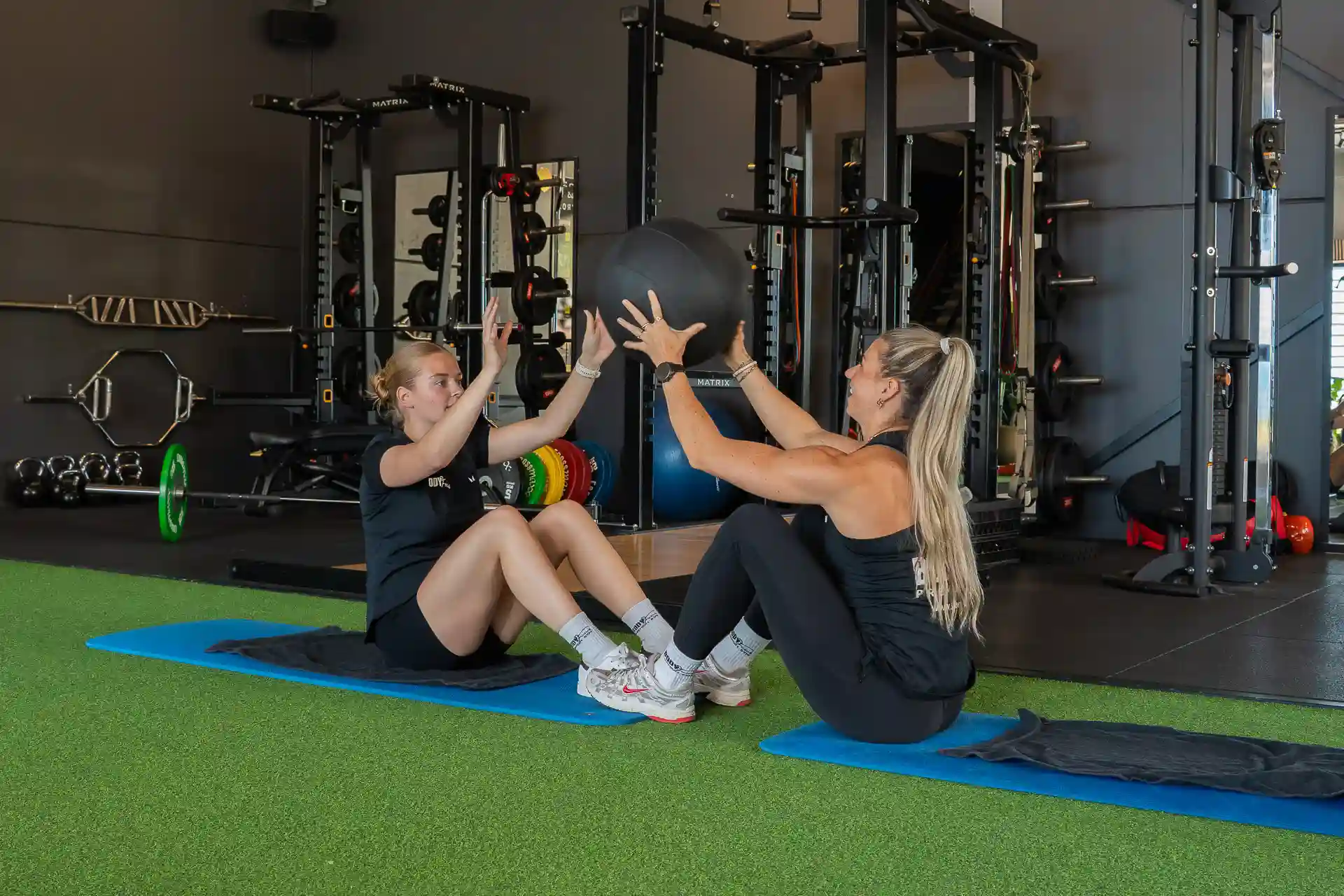 Twee vrouwen doen een medicine ball oefening tijdens small group training
