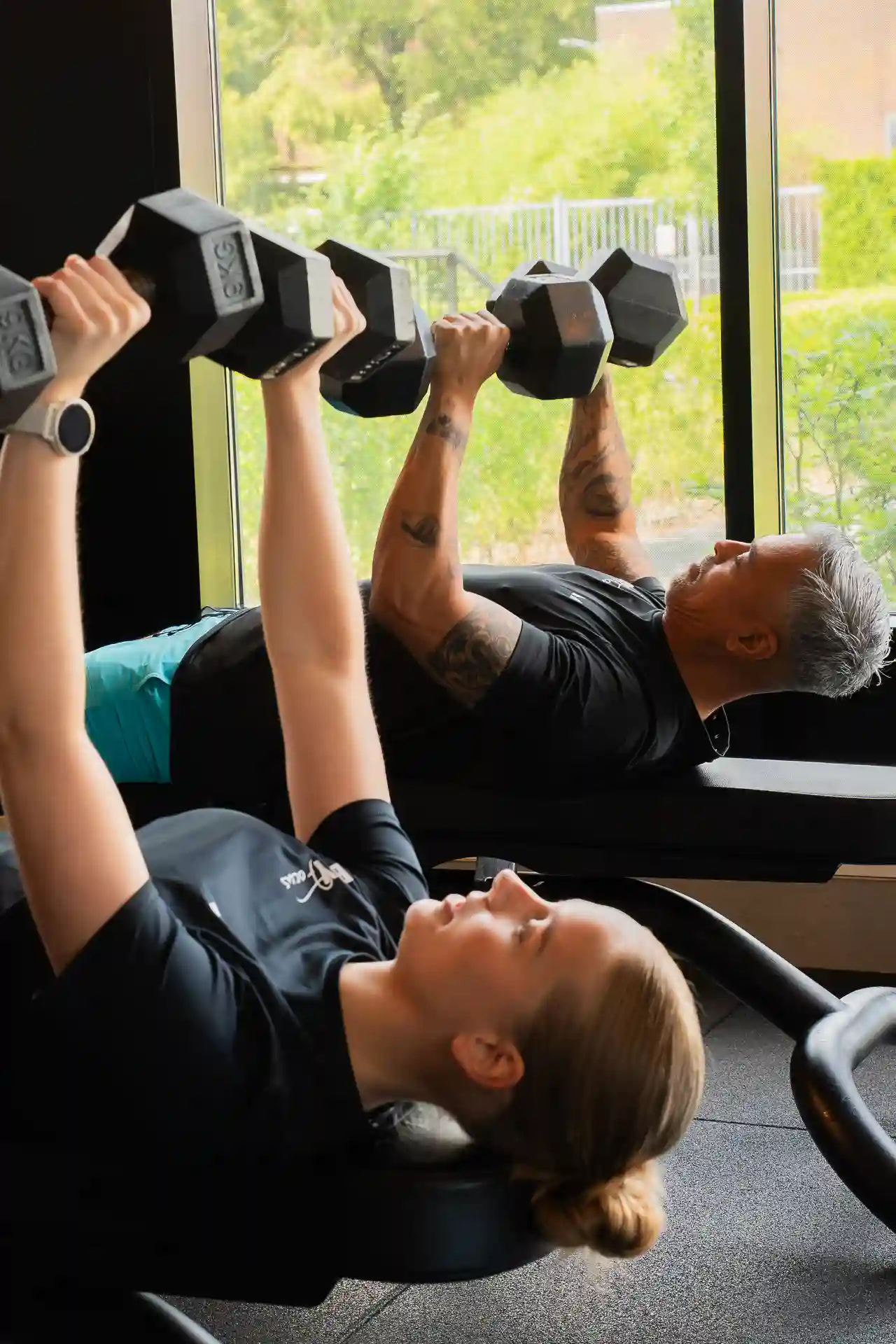 Twee sporters doen dumbbell bench press naast elkaar