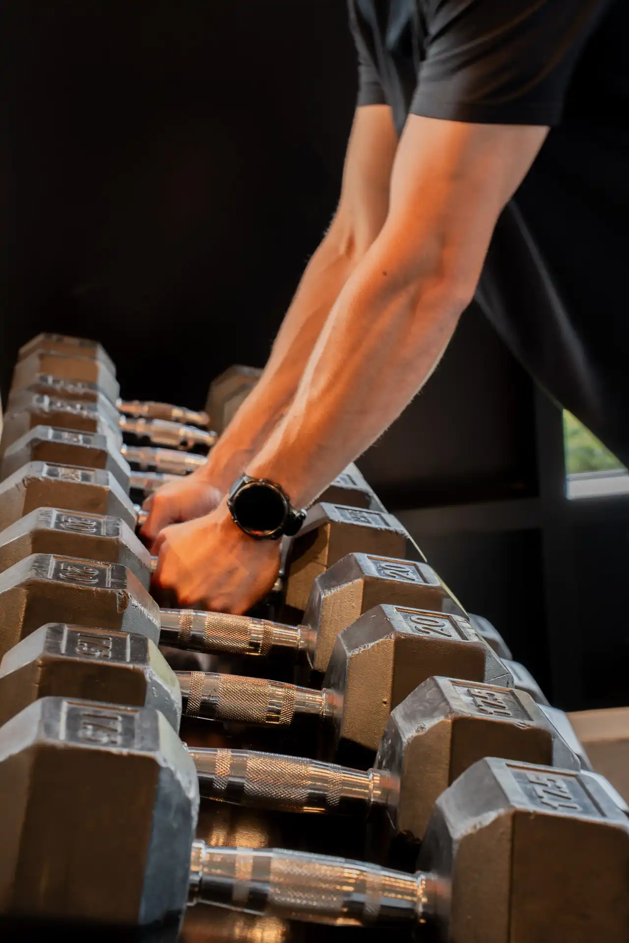 Sporter pakt een dumbbell uit het rek tijdens een training in de Open Gym