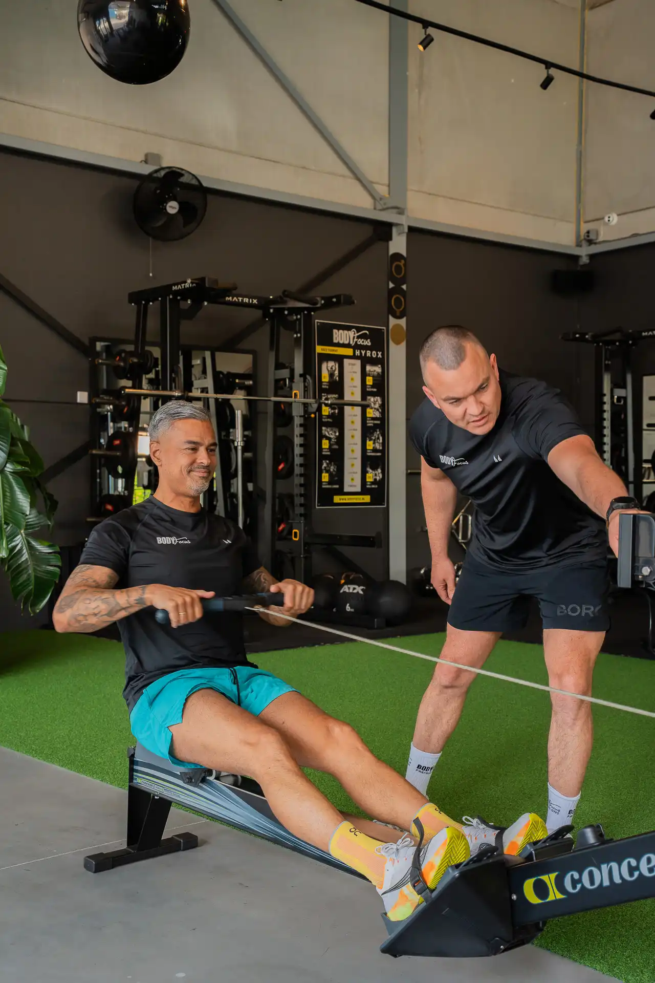 Trainer coacht member op de roeimachine tijdens conditietraining bij Body Focus