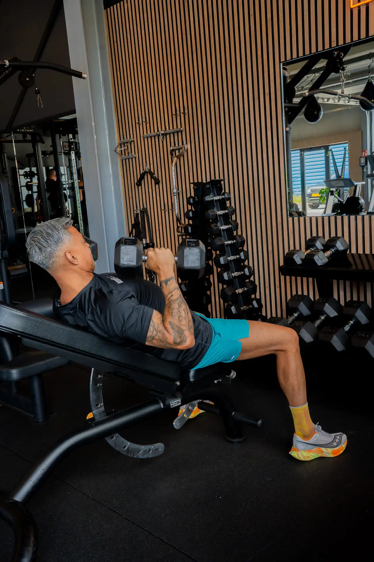 Member doet dumbbell chest press op een incline bench in de Open Gym van Body Focus