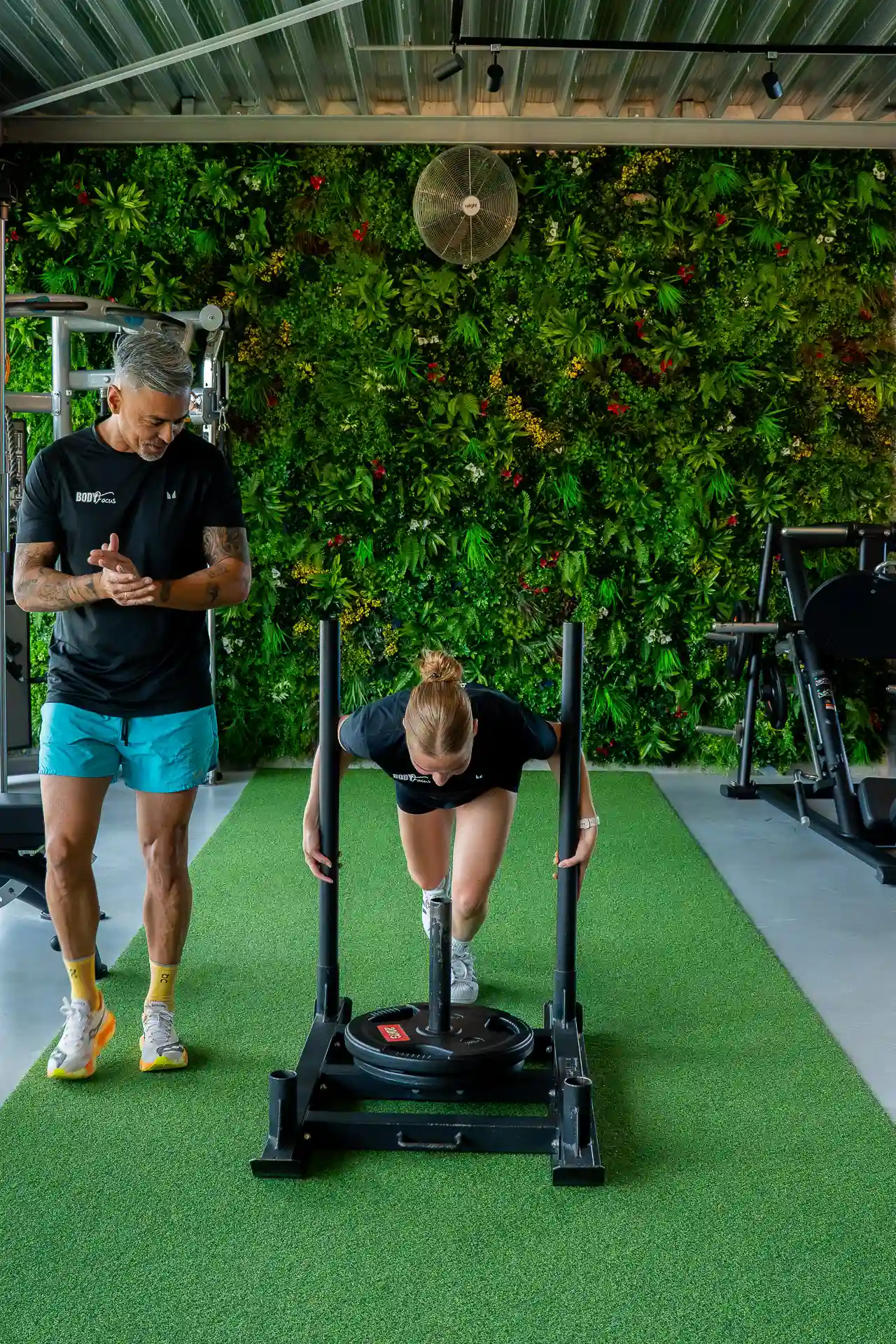 Sportmaatje duwt sled onder begeleiding van coach